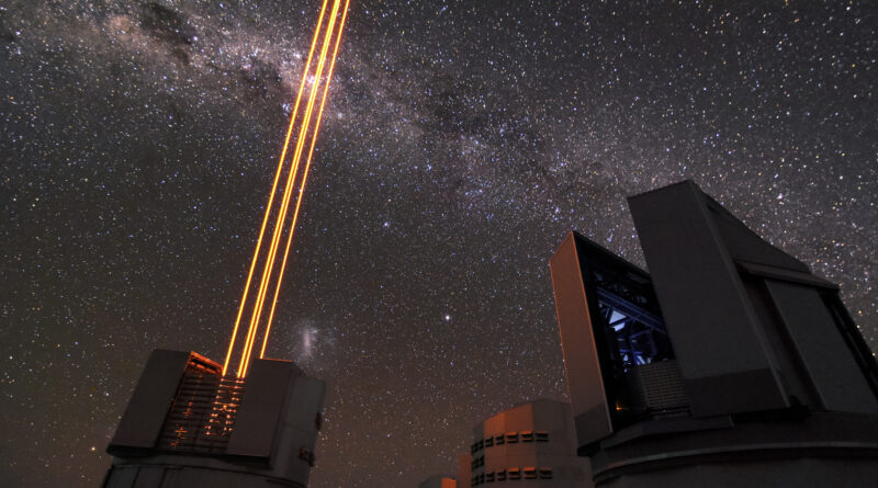 A ground-based telescope emitting a bright laser beam into the night sky as part of an adaptive optics system to create an artificial guide star for astronomical observations.